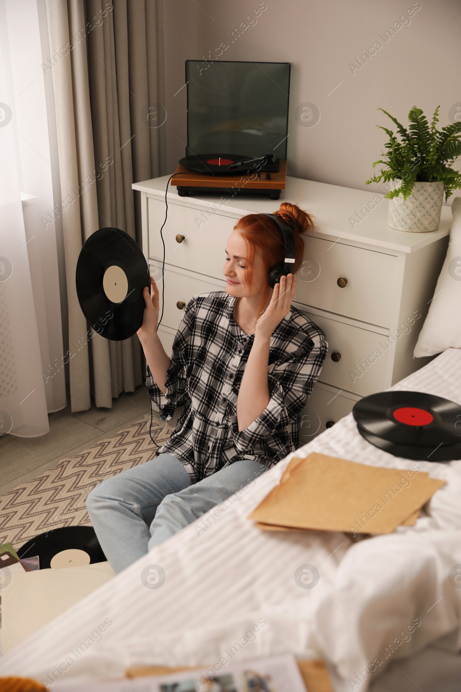 Young woman listening to music with turntable in bedroom Photo of Young woman listening to music with turntable in bedroom