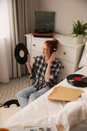 Young woman listening to music with turntable in bedroom Photo of Young woman listening to music with turntable in bedroom