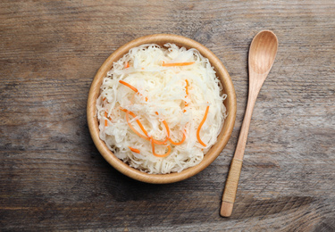 Photo of Tasty fermented cabbage on wooden table, flat lay