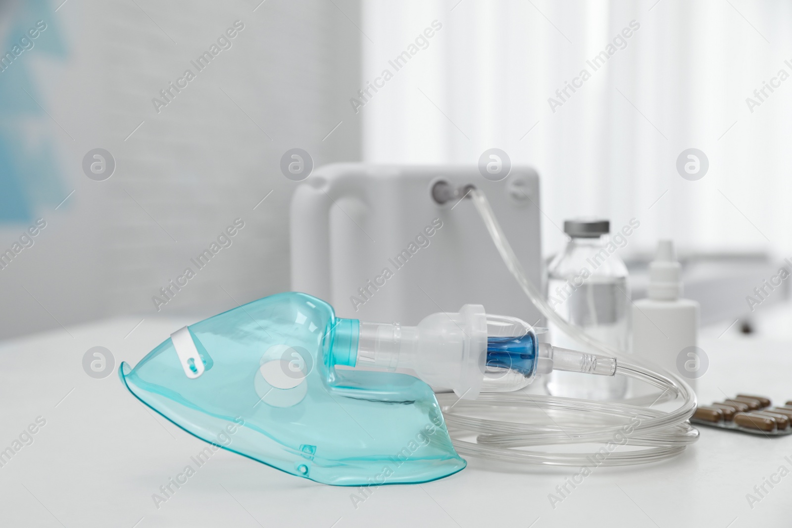 Photo of Modern nebulizer with face mask and medicines on white table indoors. Equipment for inhalation