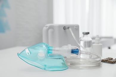 Modern nebulizer with face mask and medicines on white table indoors. Equipment for inhalation Photo of Modern nebulizer with face mask and medicines on white table indoors. Equipment for inhalation