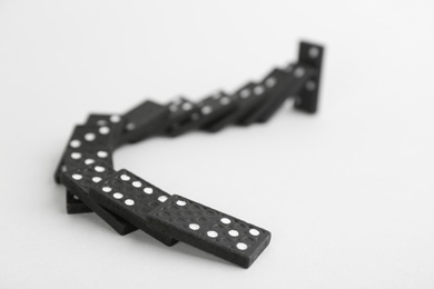 Black domino tiles falling on white background Photo of Black domino tiles falling on white background