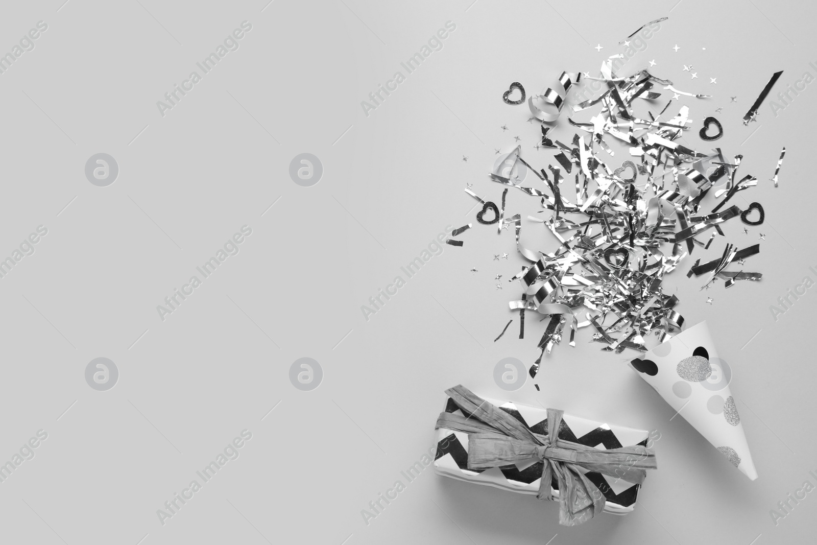 Flat lay composition with shiny silver confetti and box on light grey background. Space for text Photo of Flat lay composition with shiny silver confetti and box on light grey background. Space for text