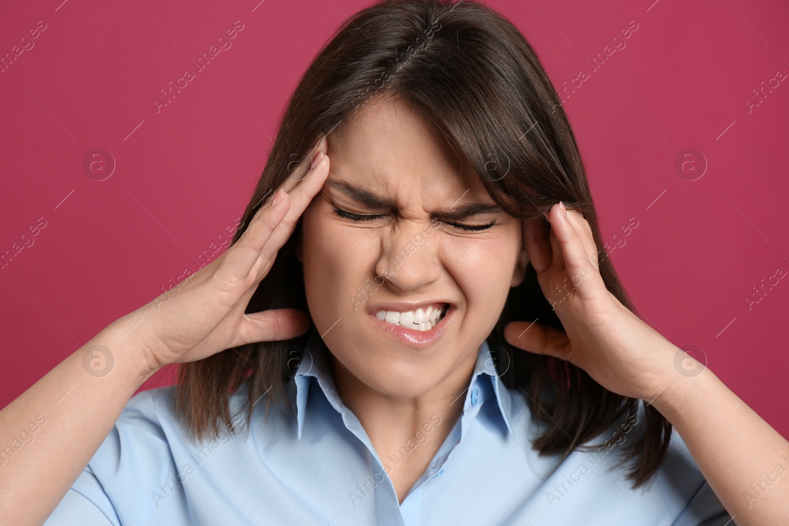 Young woman suffering from migraine on crimson background Photo of Young woman suffering from migraine on crimson background