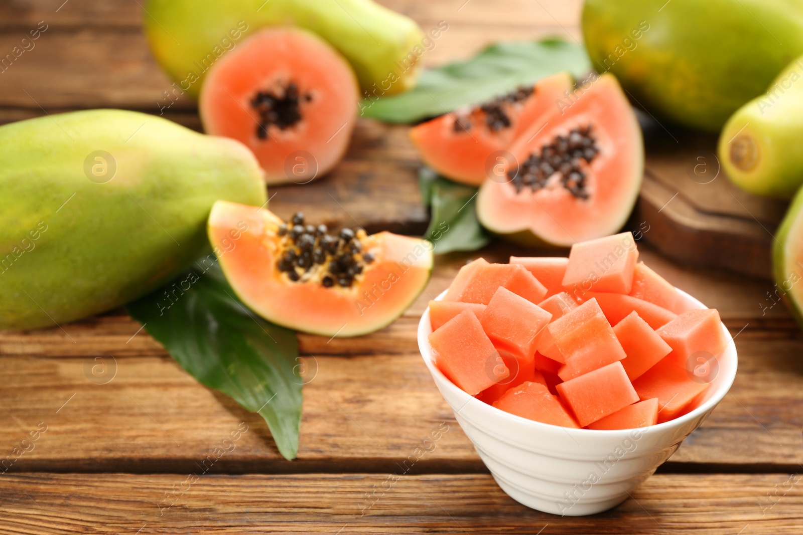 Fresh diced papaya fruit in bowl on wooden table Photo of Fresh diced papaya fruit in bowl on wooden table