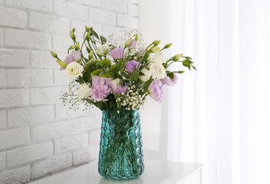 Bouquet of beautiful Eustoma flowers on table near white brick wall Photo of Bouquet of beautiful Eustoma flowers on table near white brick wall