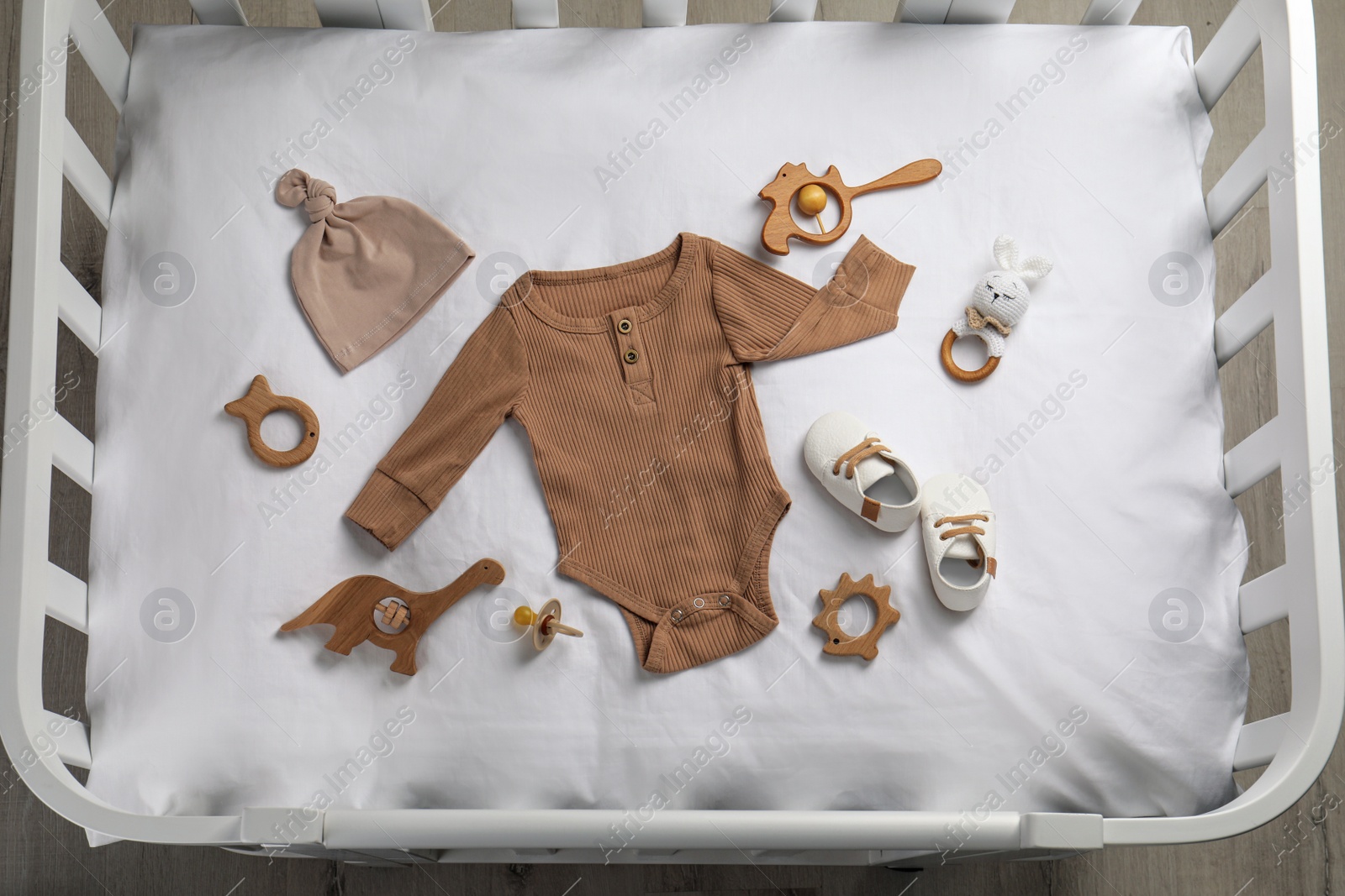 Flat lay composition with cute baby clothes and accessories on white bedsheet in crib Photo of Flat lay composition with cute baby clothes and accessories on white bedsheet in crib