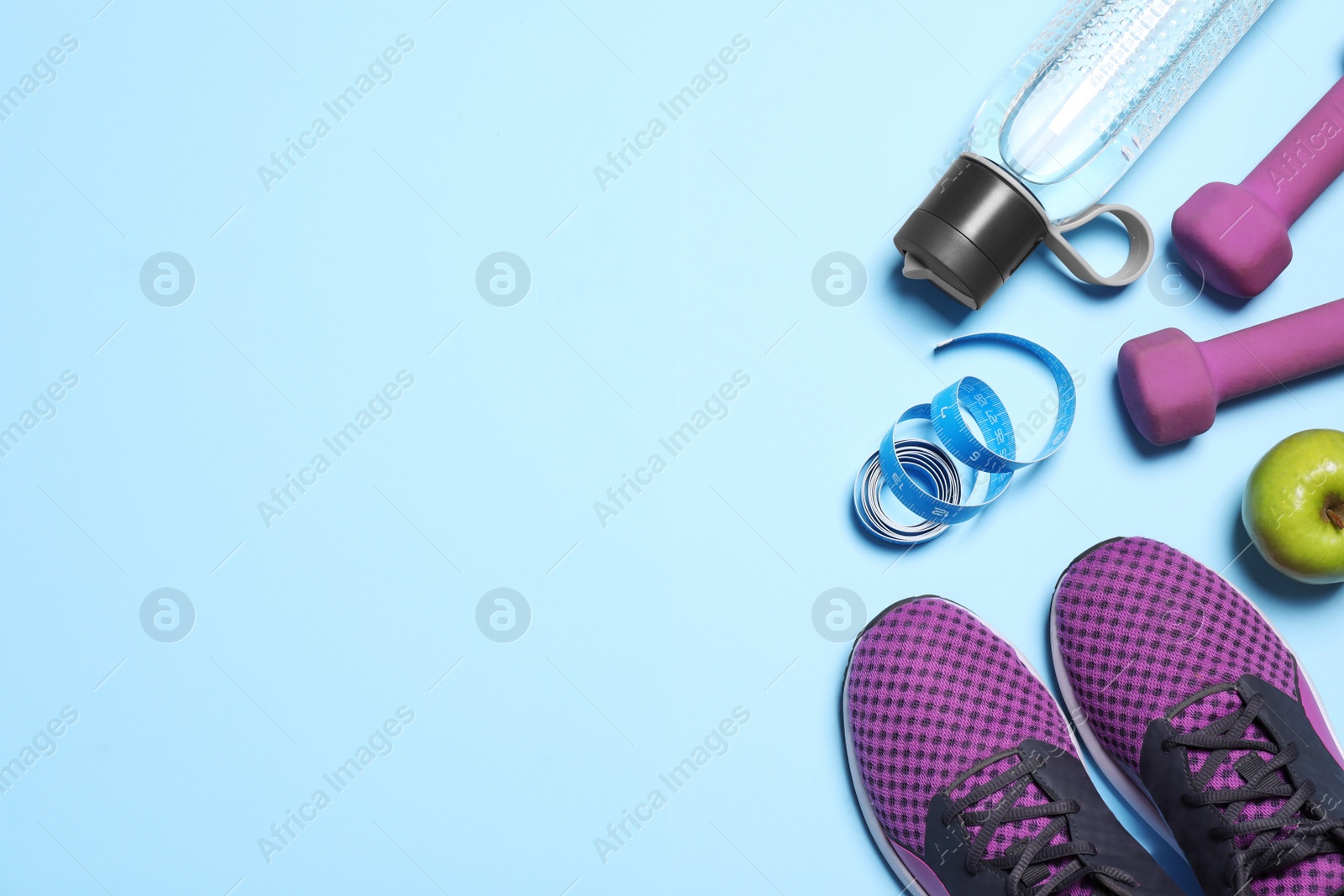 Flat lay composition with sneakers and dumbbells on light blue background. Space for text Photo of Flat lay composition with sneakers and dumbbells on light blue background. Space for text