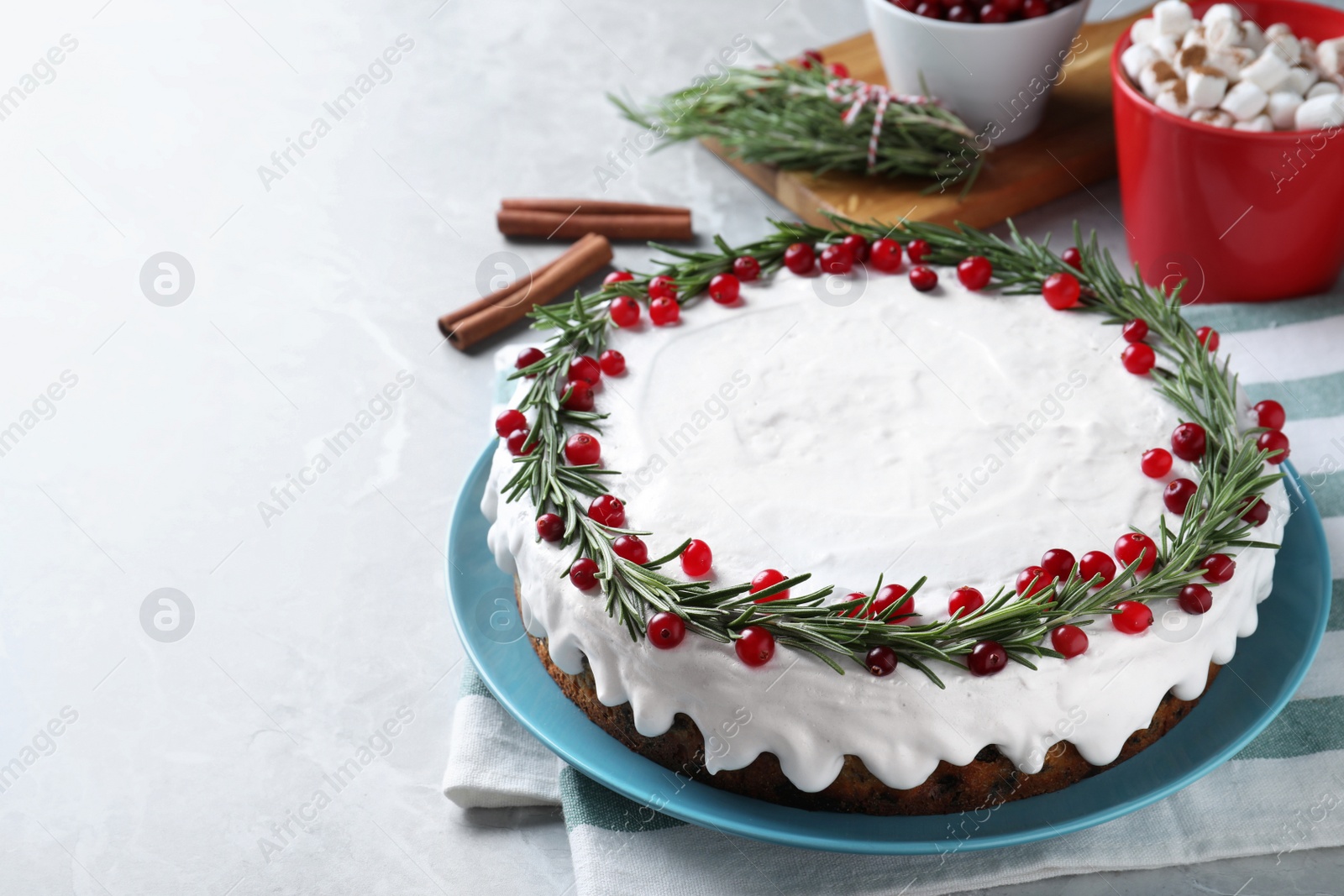 Traditional Christmas cake decorated with rosemary and cranberries on light grey marble table, space for text Photo of Traditional Christmas cake decorated with rosemary and cranberries on light grey marble table, space for text