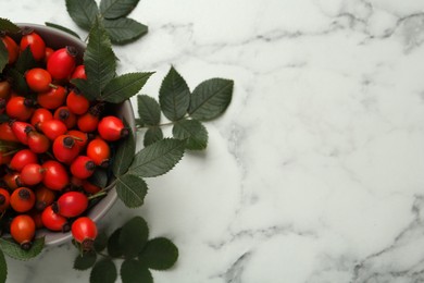 Ripe rose hip berries with green leaves on white marble table, flat lay. Space for text Photo of Ripe rose hip berries with green leaves on white marble table, flat lay. Space for text