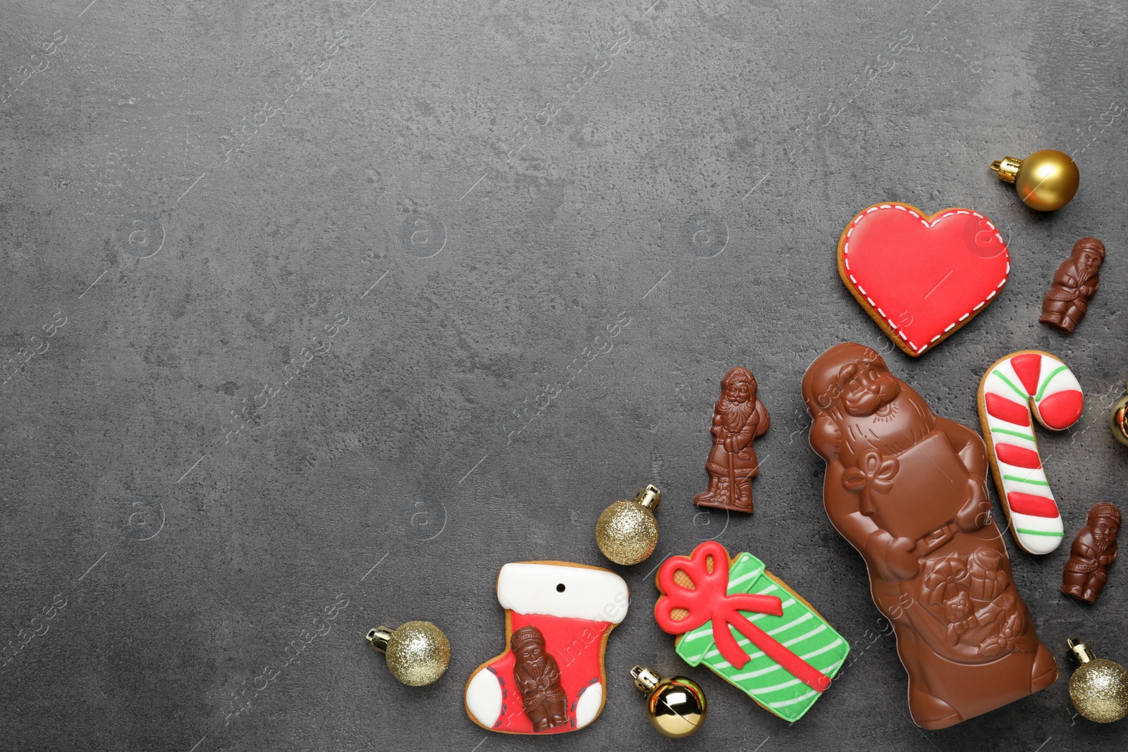 Flat lay composition with chocolate Santa Claus candies and Christmas cookies on grey table, space for text Photo of Flat lay composition with chocolate Santa Claus candies and Christmas cookies on grey table, space for text