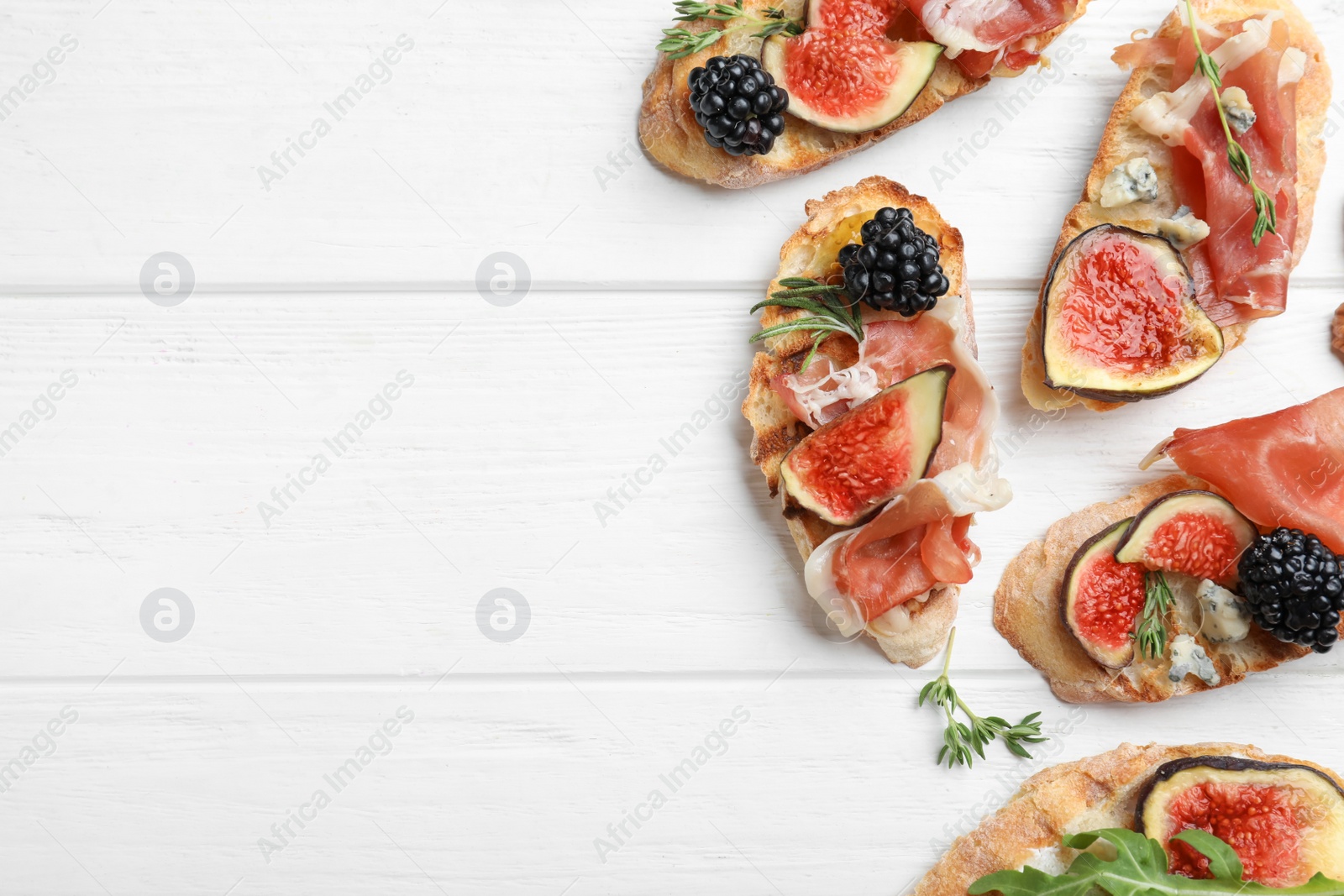 Sandwiches with ripe figs and prosciutto served on white wooden table, flat lay. Space for text Photo of Sandwiches with ripe figs and prosciutto served on white wooden table, flat lay. Space for text