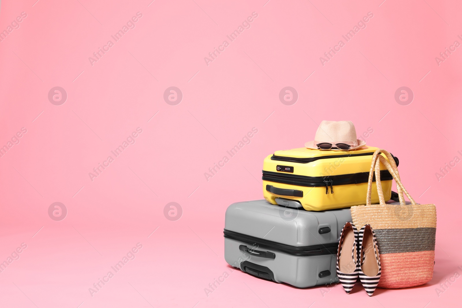 Photo of Stylish suitcases with beach accessories on pink background. Space for text