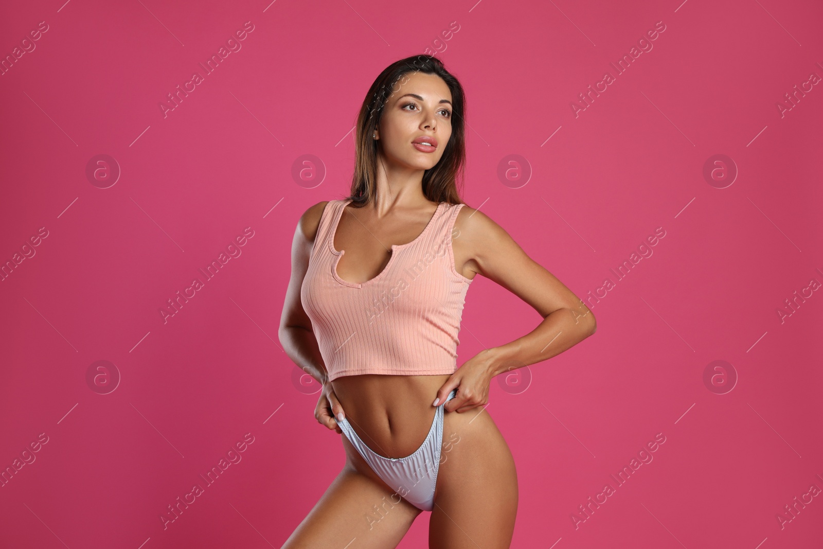Beautiful woman in white sexy panties and top on pink background Photo of Beautiful woman in white sexy panties and top on pink background