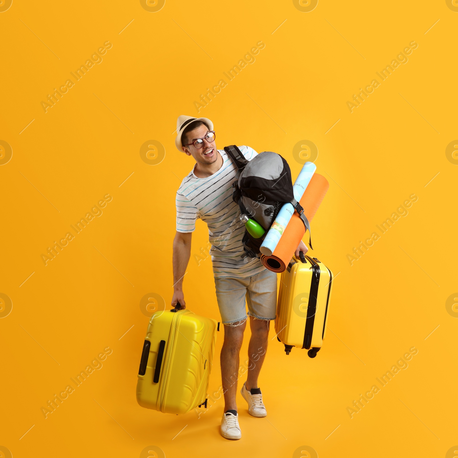Male tourist with travel backpack and suitcases on yellow background Photo of Male tourist with travel backpack and suitcases on yellow background