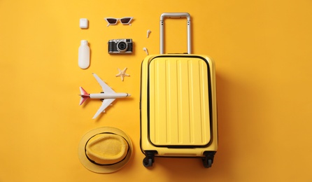 Flat lay composition with suitcase and travel accessories on yellow background. Summer vacation Photo of Flat lay composition with suitcase and travel accessories on yellow background. Summer vacation