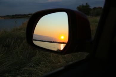 Reflection of landscape with beautiful sunset over calm river in car side view mirror, closeup Photo of Reflection of landscape with beautiful sunset over calm river in car side view mirror, closeup