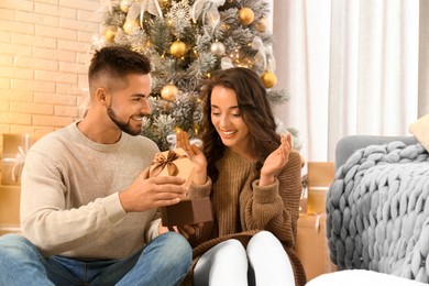 Young man presenting Christmas gift to his girlfriend at home Image of Young man presenting Christmas gift to his girlfriend at home