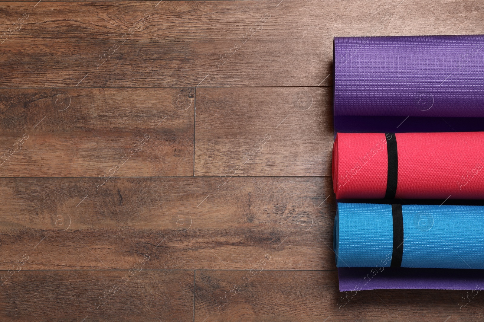 Bright rolled camping mats on wooden background, flat lay. Space for text Photo of Bright rolled camping mats on wooden background, flat lay. Space for text