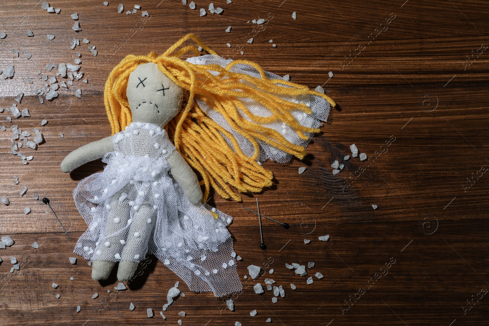 Bride voodoo doll with pins and salt on wooden background, flat lay Photo of Bride voodoo doll with pins and salt on wooden background, flat lay