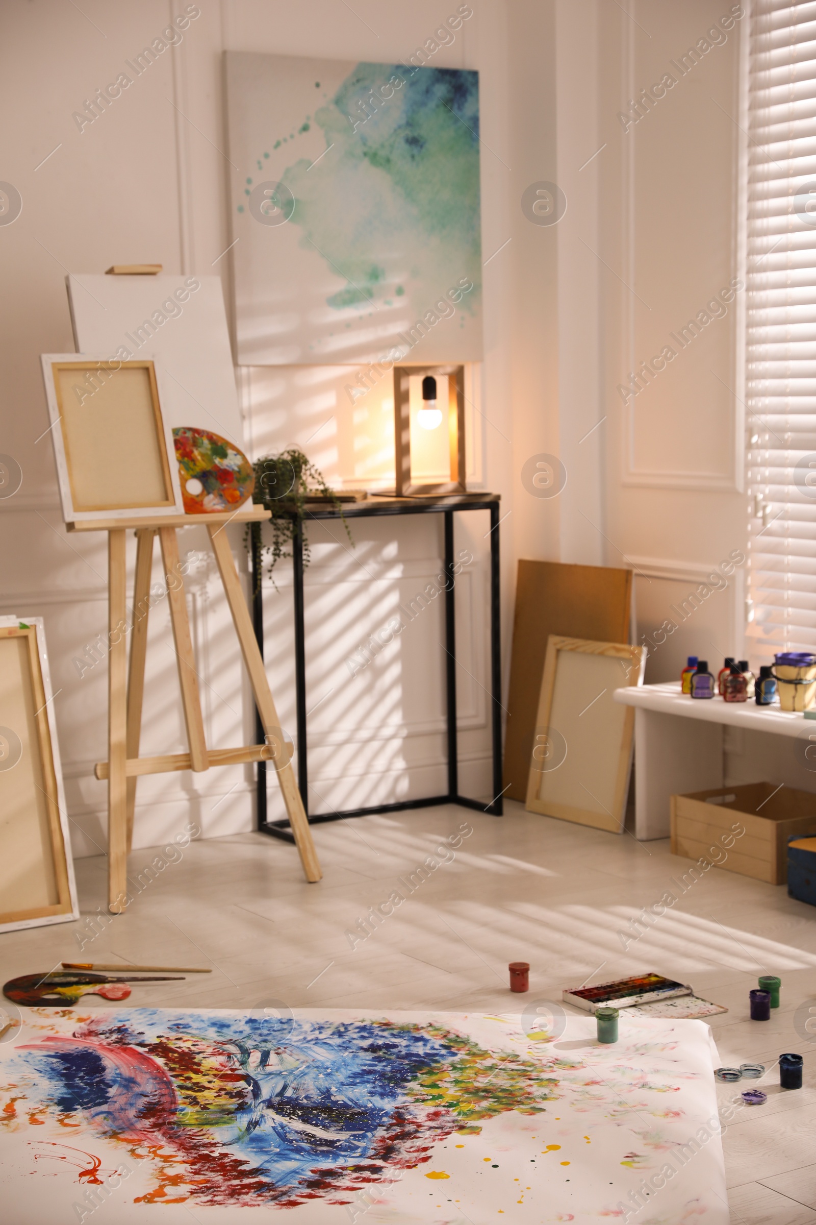 Wooden easel and abstract picture in art studio Photo of Wooden easel and abstract picture in art studio