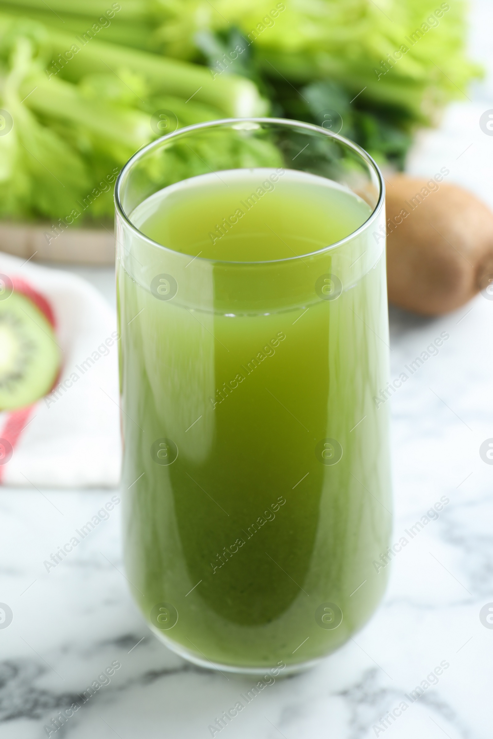 Glass with fresh celery juice on white marble table, closeup Photo of Glass with fresh celery juice on white marble table, closeup