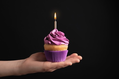 Woman holding birthday cupcake on black background Photo of Woman holding birthday cupcake on black background