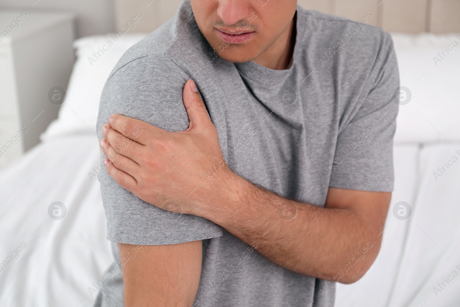 Man suffering from shoulder pain at home, closeup Photo of Man suffering from shoulder pain at home, closeup