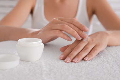 Woman applying cream onto hand on white towel, closeup Photo of Woman applying cream onto hand on white towel, closeup