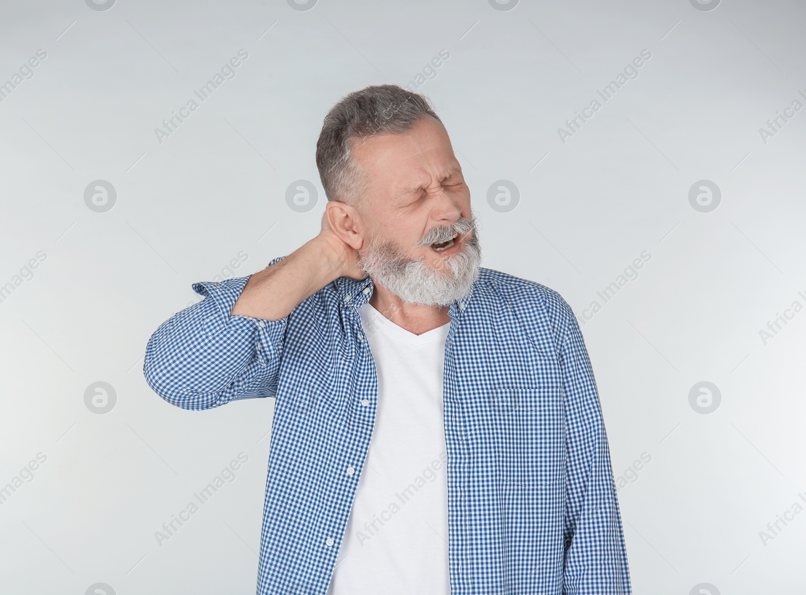 Man suffering from neck pain on light background Photo of Man suffering from neck pain on light background