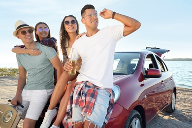 Happy friends near car on beach. Summer trip Photo of Happy friends near car on beach. Summer trip