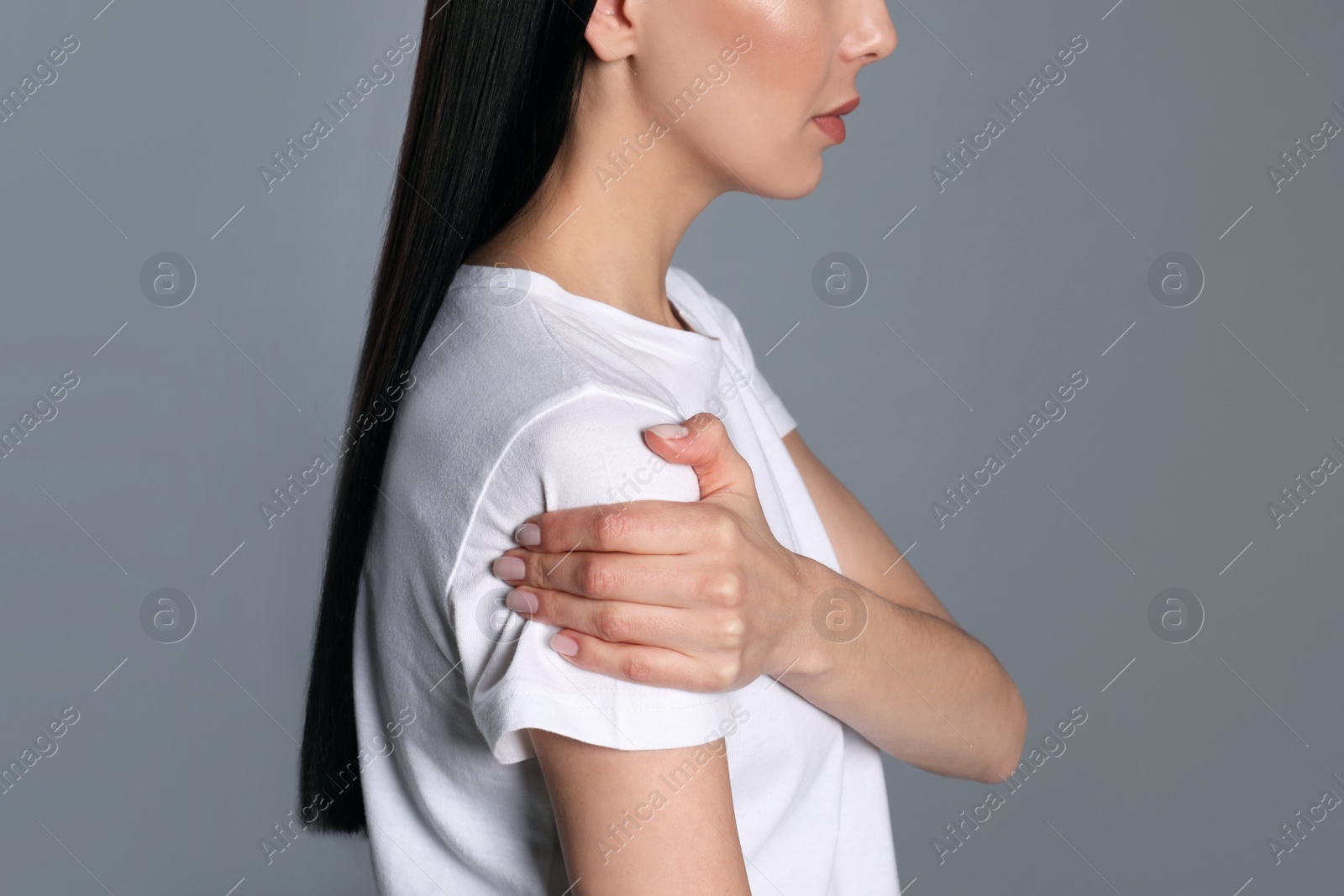 Woman suffering from shoulder pain on grey background, closeup Photo of Woman suffering from shoulder pain on grey background, closeup