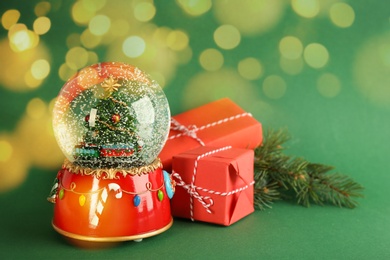 Beautiful Christmas snow globe, gift boxes and fir tree branch on green background, bokeh effect. Space for text Image of Beautiful Christmas snow globe, gift boxes and fir tree branch on green background, bokeh effect. Space for text