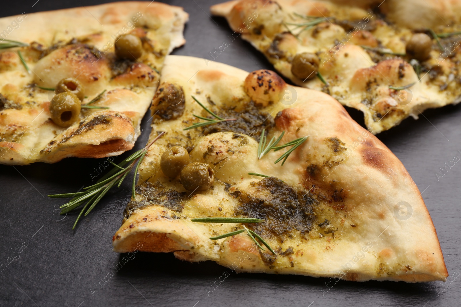 Delicious focaccia bread with green olives on slate board, closeup Photo of Delicious focaccia bread with green olives on slate board, closeup