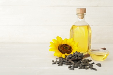 Sunflower, oil and seeds on white wooden table, space for text Photo of Sunflower, oil and seeds on white wooden table, space for text