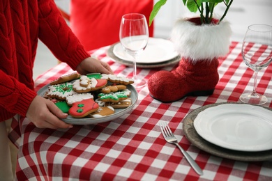 Woman with cookies setting table for Christmas dinner indoors, closeup Photo of Woman with cookies setting table for Christmas dinner indoors, closeup