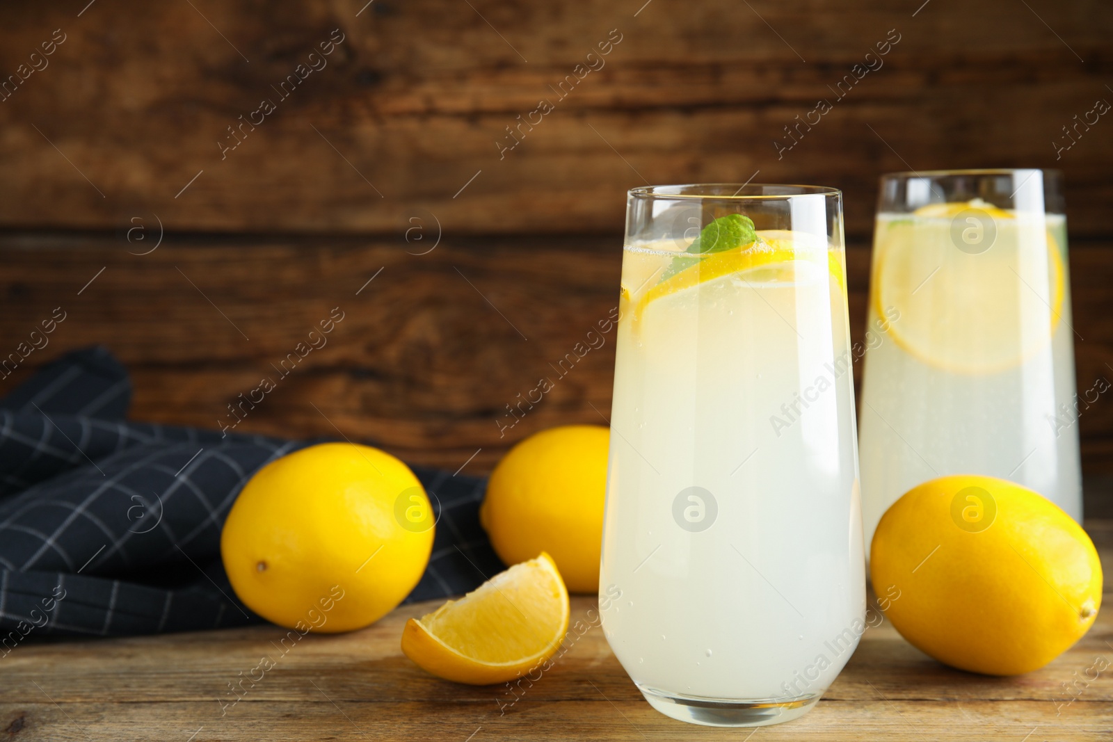 Photo of Cool freshly made lemonade and fruits on wooden table. Space for text