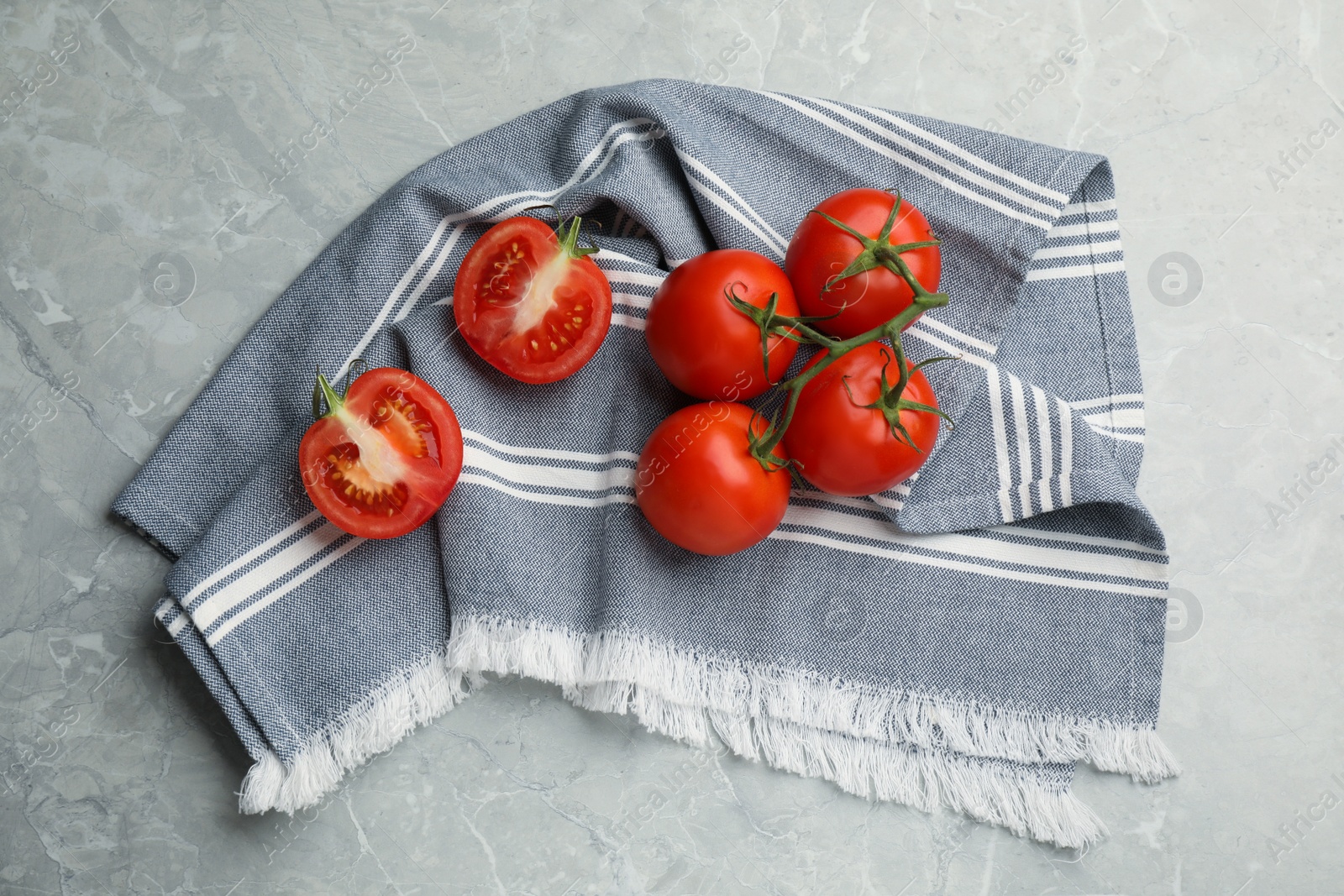 Kitchen towel and fresh tomatoes on grey table, flat lay Photo of Kitchen towel and fresh tomatoes on grey table, flat lay