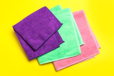 Colorful microfiber cloths on yellow background, flat lay Photo of Colorful microfiber cloths on yellow background, flat lay
