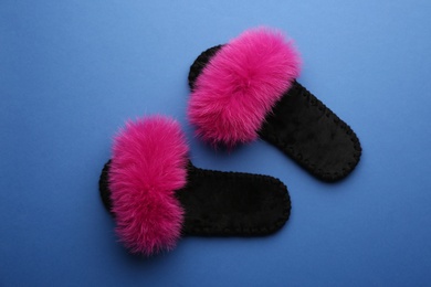 Pair of soft slippers on blue background, flat lay Photo of Pair of soft slippers on blue background, flat lay