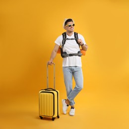 Male tourist with travel backpack and suitcase on yellow background Photo of Male tourist with travel backpack and suitcase on yellow background