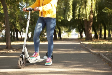 Woman riding electric kick scooter outdoors. Space for text Photo of Woman riding electric kick scooter outdoors. Space for text