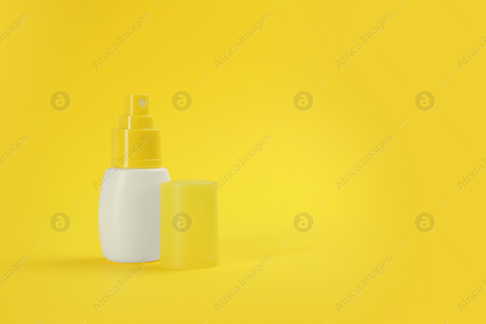 Bottle with insect repellent spray on yellow background, space for text Photo of Bottle with insect repellent spray on yellow background, space for text