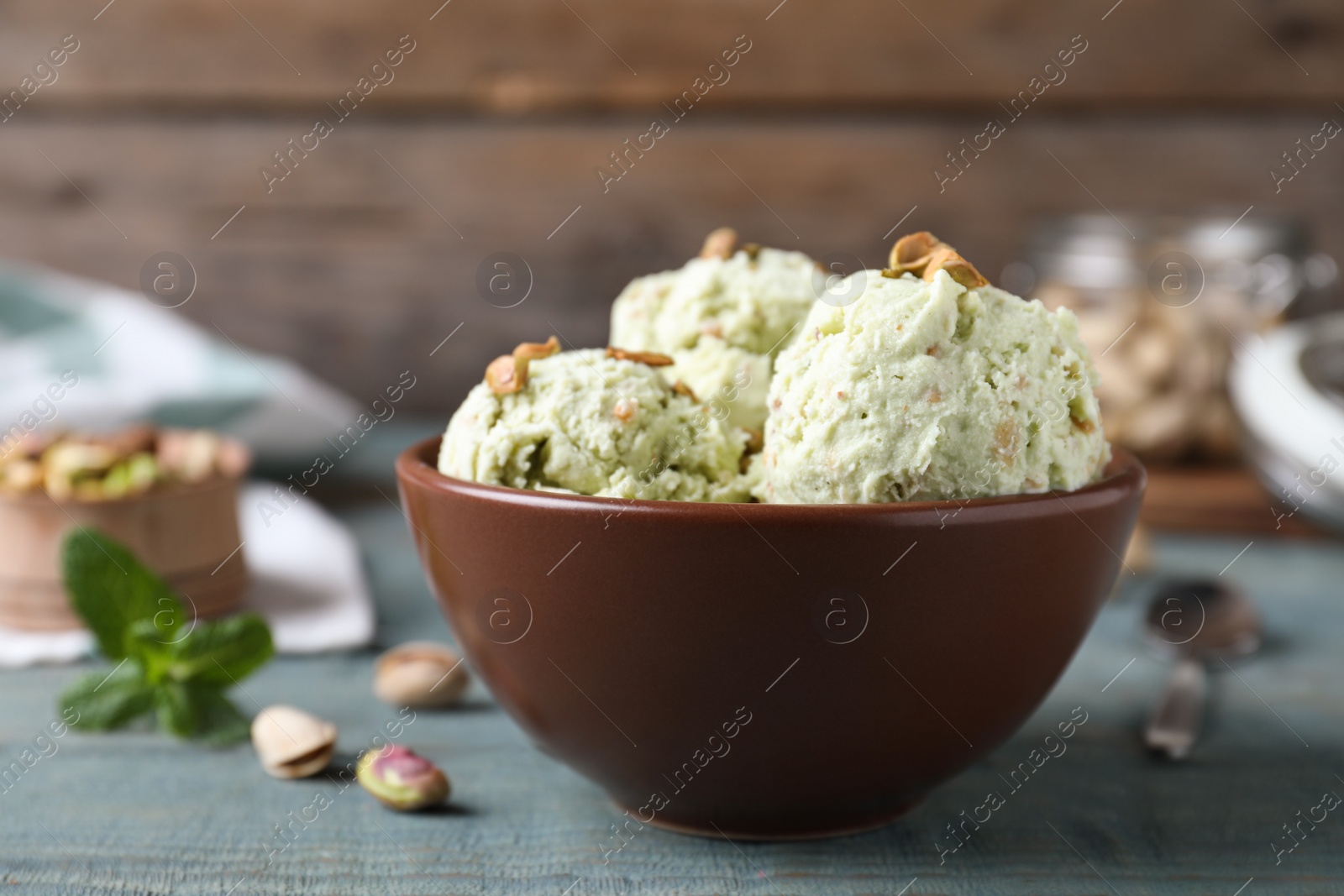 Delicious pistachio ice cream in bowl on blue wooden table Photo of Delicious pistachio ice cream in bowl on blue wooden table
