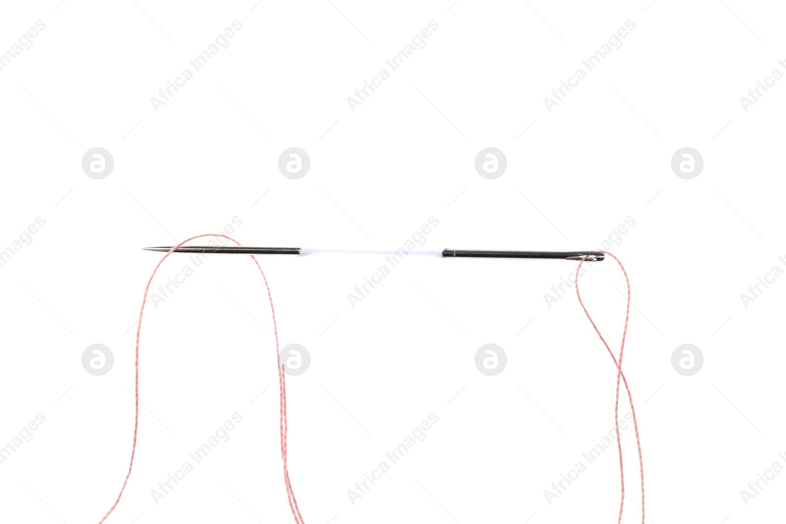 Sewing needle with thread piercing white paper, top view Photo of Sewing needle with thread piercing white paper, top view