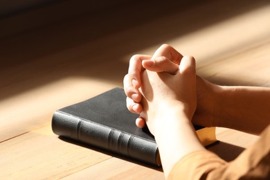 Religious woman praying over Bible indoors, closeup Photo of Religious woman praying over Bible indoors, closeup