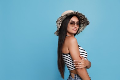Beautiful young woman with straw hat and stylish sunglasses on light blue background. Space for text Photo of Beautiful young woman with straw hat and stylish sunglasses on light blue background. Space for text