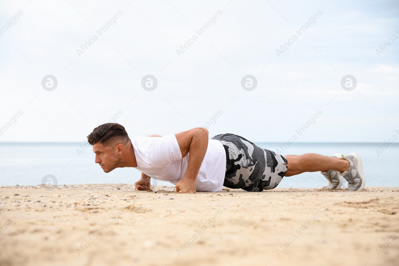 Muscular man doing push up on beach. Body training Photo of Muscular man doing push up on beach. Body training
