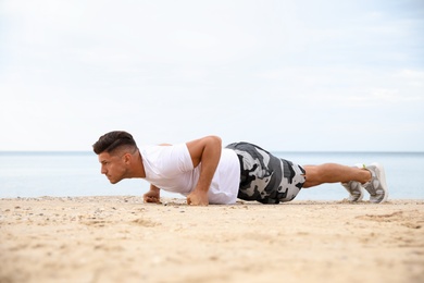 Muscular man doing push up on beach. Body training Photo of Muscular man doing push up on beach. Body training