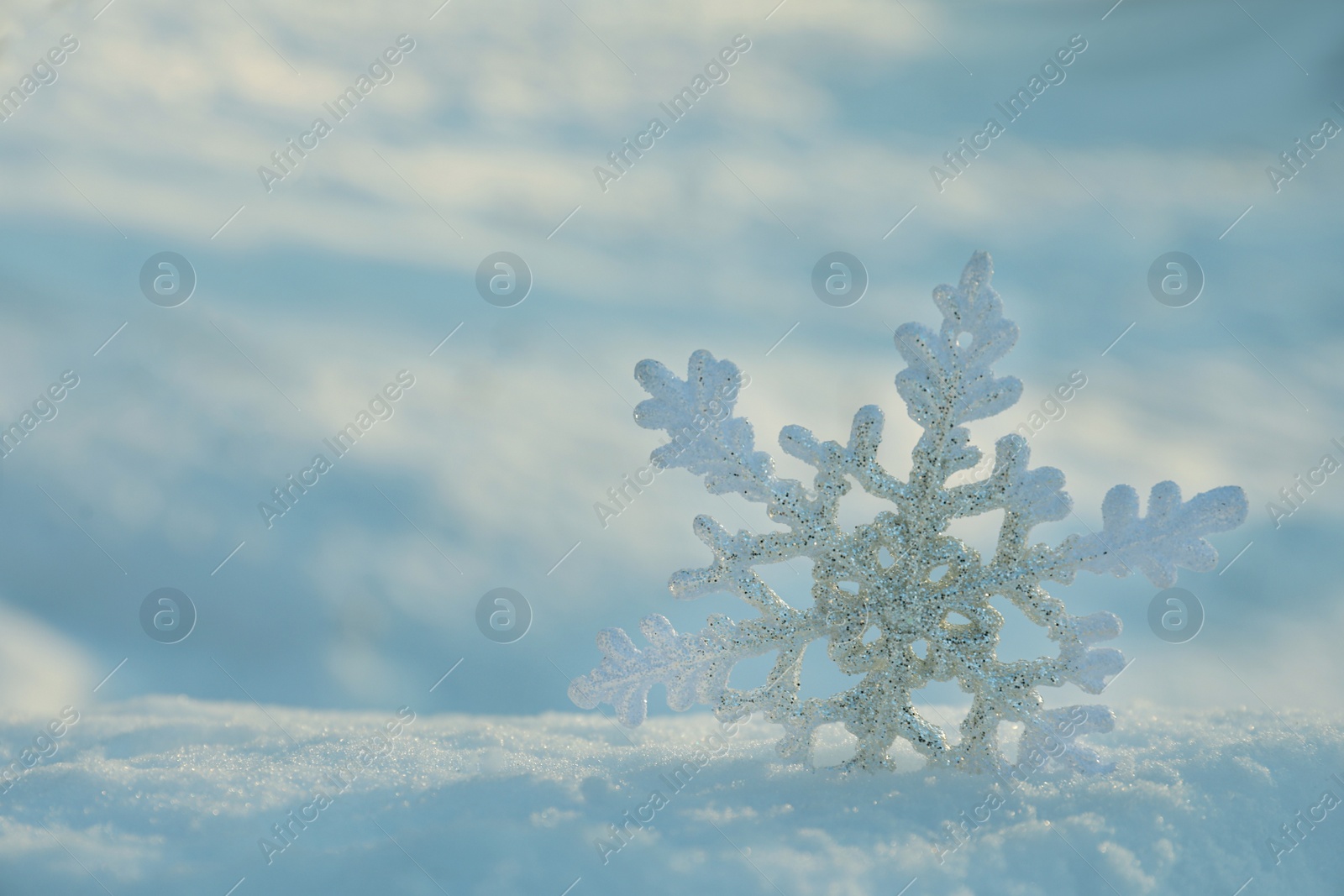 Beautiful decorative snowflake in white snow, outdoors. Space for text Photo of Beautiful decorative snowflake in white snow, outdoors. Space for text